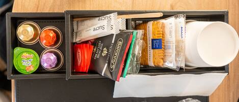 A drawer with various food items and a cup.