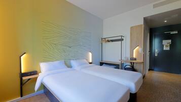 Une chambre d’hôtel avec un grand lit, des tables de chevet, un bureau et une lampe fixée au mur.