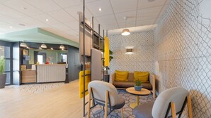 Una zona de recepción moderna con mostrador, asientos y un muro decorado.