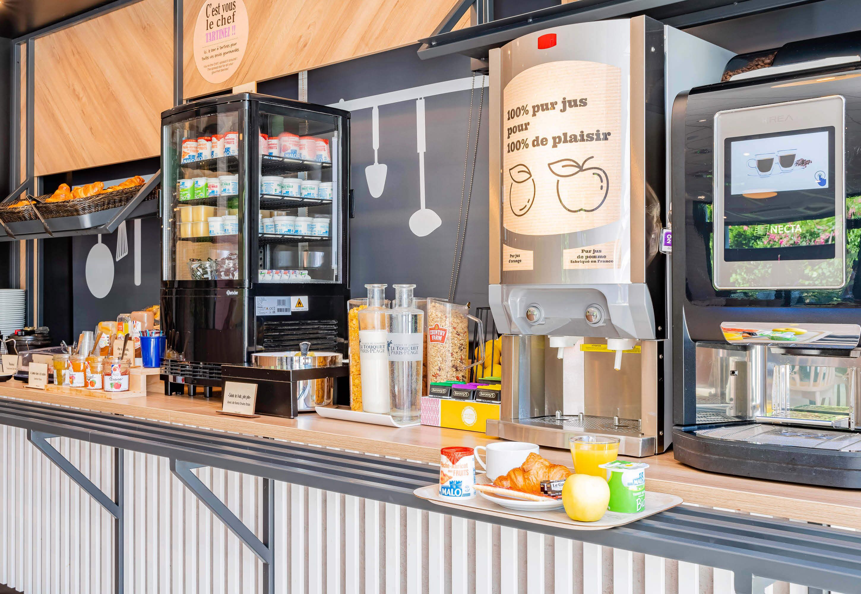 A breakfast bar with a coffee machine, a refrigerator stocked with food, and a sign indicating 100% fresh ingredients.