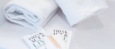 A white bathroom sink with two rolled-up white towels and a magazine titled "Think & Act".