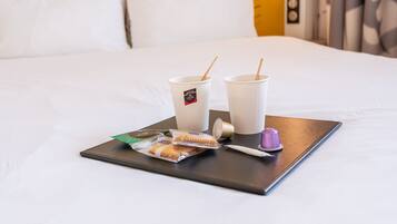 Un plateau avec deux tasses, une brosse à dents, un savon et un paquet de biscuits sur un lit.