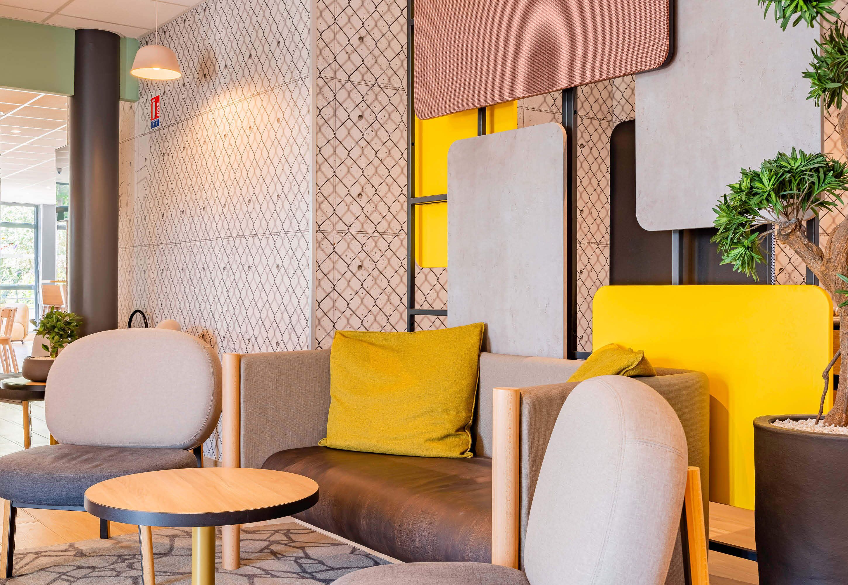 Un espace de détente moderne comprenant un canapé, deux fauteuils et une petite table ronde.