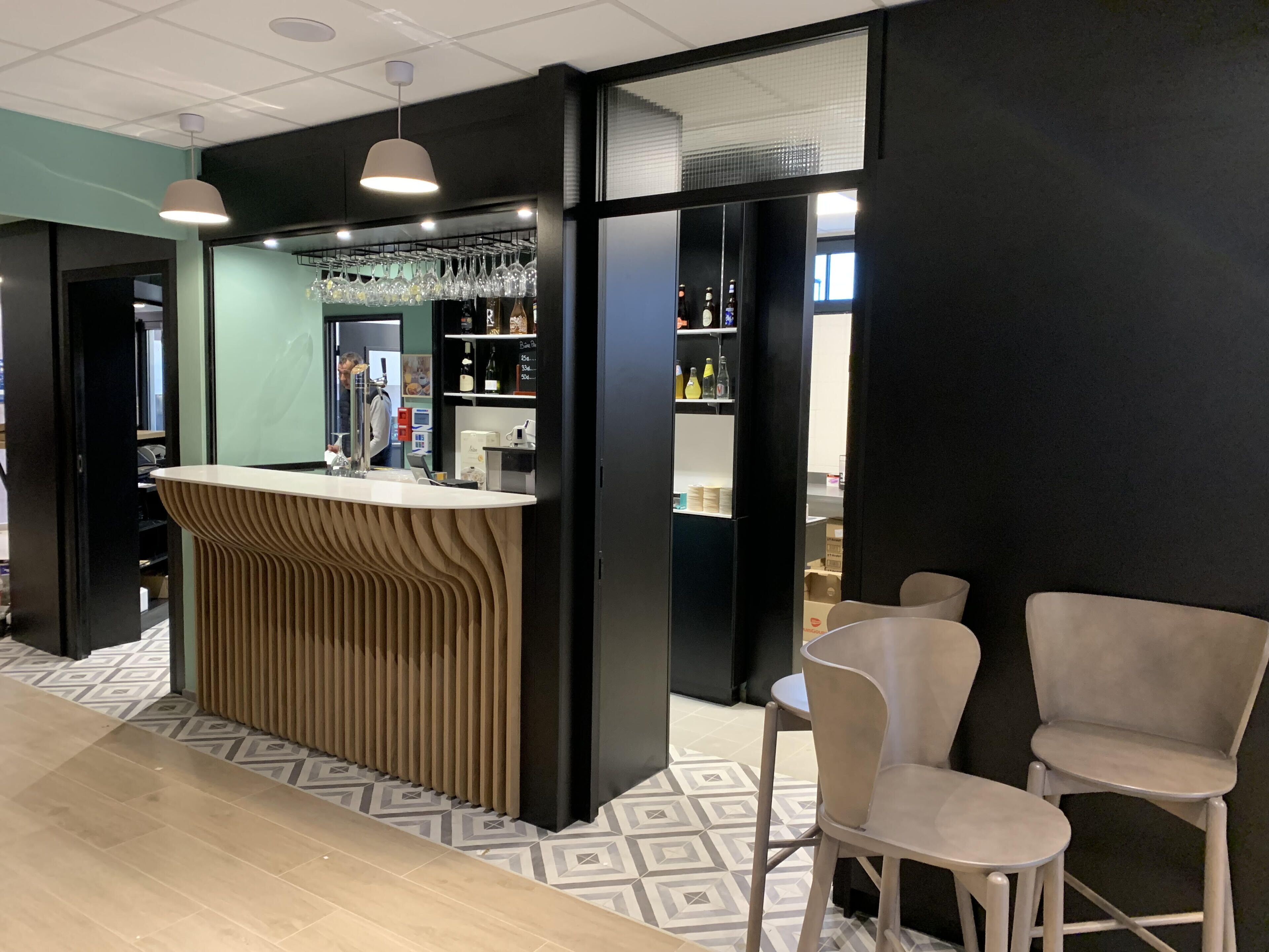 Una zona de bar moderna con mostrador de madera, taburetes y una vitrina de vidrio.