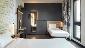 A modern hotel room with a large bed, a smaller bed, a desk, and a mirror. - B&B HOTEL Argenteuil (Argenteuil)
