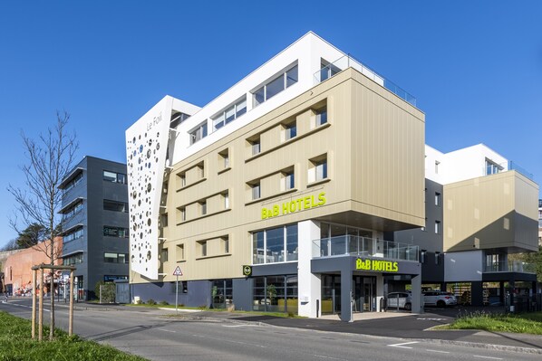 Um hotel tipo bed and breakfast com design moderno, apresentando um telhado plano, grandes janelas e uma placa.