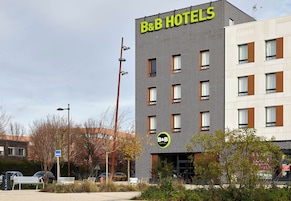 A B&B hotel with a modern brick facade, multiple windows, and a sign indicating it is a bed and breakfast.
