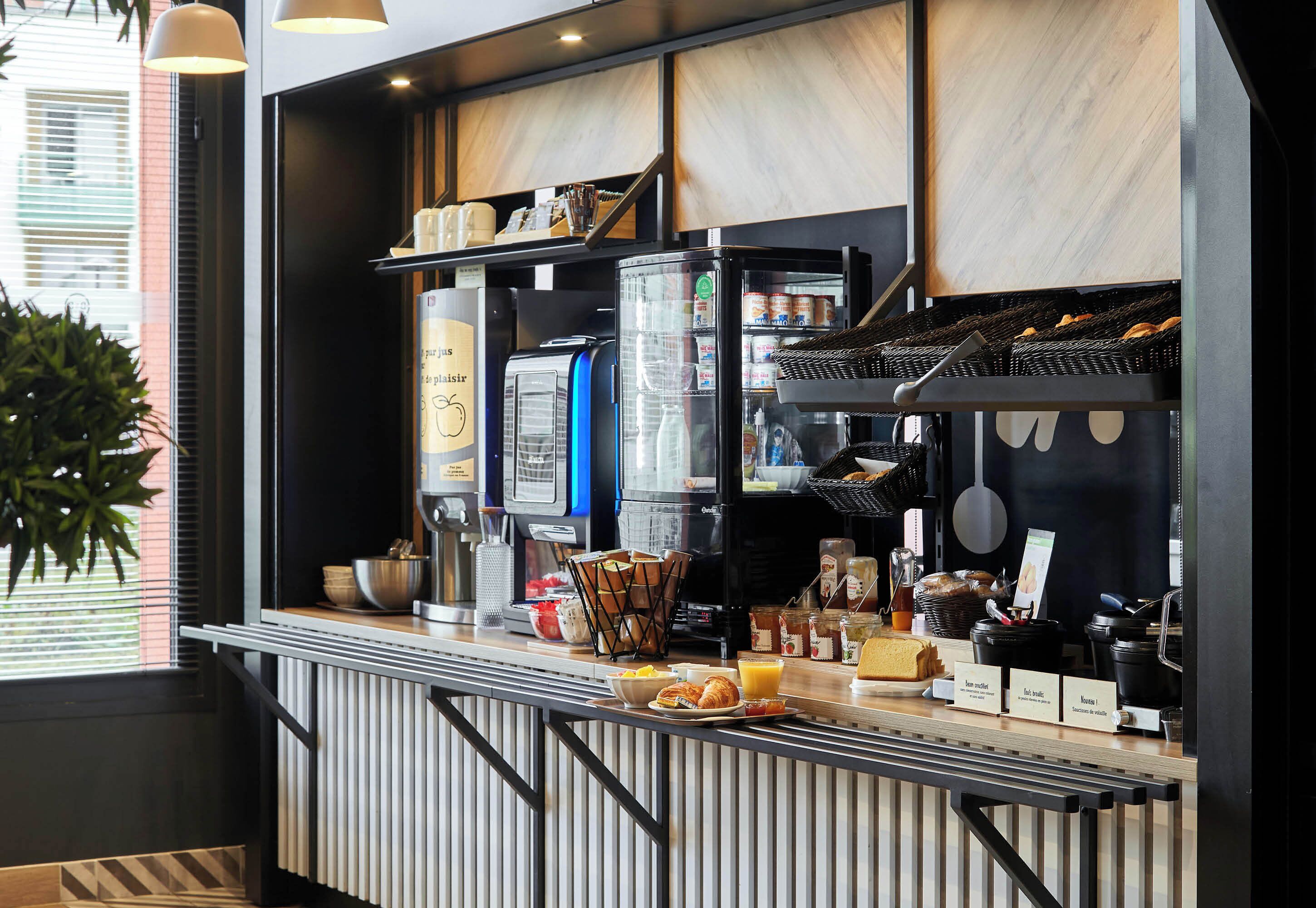 Een ontbijtbuffet met een koffieapparaat, diverse etenswaren en toevoegingen.