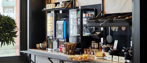 Een ontbijtbuffet met een koffieapparaat, diverse etenswaren en toevoegingen.