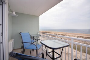 Ein Balkon mit Tisch und Stühlen, mit Blick auf einen Strand.