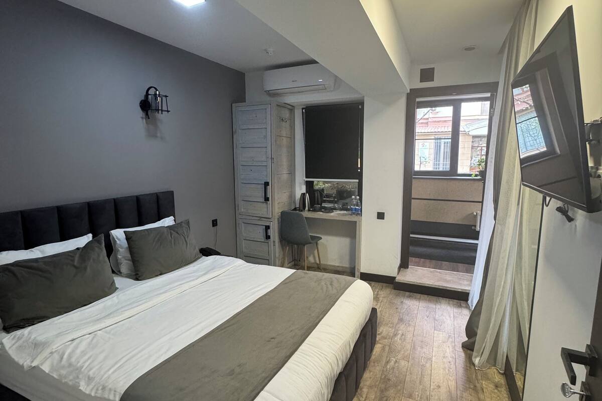 A bedroom with a large bed, a desk, and a TV.