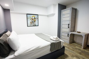 Een moderne slaapkamer met een bed, een bureau en een schilderij aan de muur.