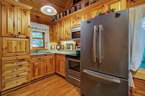 Enjoy cooking in this well-equipped kitchen with a refrigerator, oven, and microwave, and take in the view of the surrounding greenery.