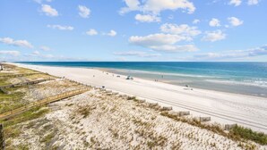 Ein Strand mit sandigem Ufer und einer hölzernen Promenade, die zum Wasser führt.