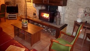 Ein gemütliches Wohnzimmer mit Kamin aus Stein, Holzmöbeln und einem Fernseher.