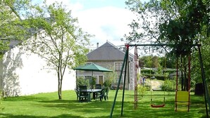 Ein Garten mit Schaukel, Esstisch und Stühlen.