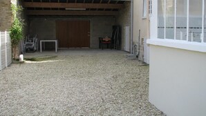 A covered outdoor area with a gravel floor, a wooden door, and a table. - 1843 LE RUISSEAU DU MOULIN (SEUIL)