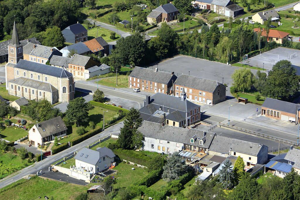 Ett flygbildsfoto av en liten stad med en framträdande kyrka, bostadshus och en stor parkeringsplats.