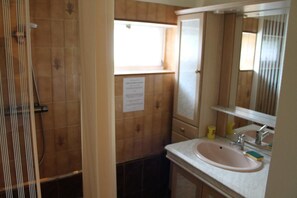 Un baño con ducha, lavamanos y espejo.