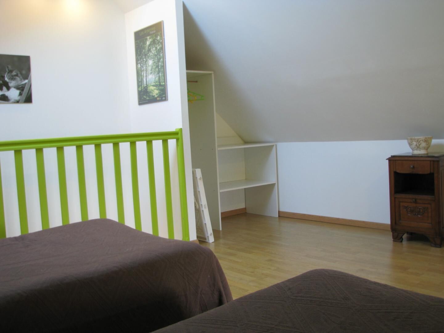 Een kamer met twee bedden, een witte inbouwkast en een klein houten kastje.