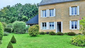 Ein zweistöckiges Steinhaus mit gepflegtem Rasen und Garten.