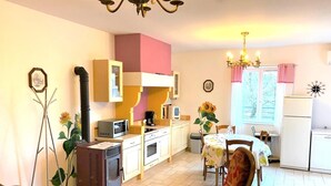 A compact kitchen with a dining area, featuring a microwave, oven, and a small refrigerator.