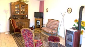 A living room with a wooden cabinet, a television, a sofa, a chair, a small table, and a fireplace.
