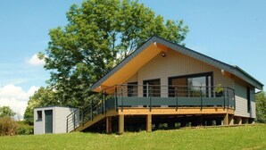 A modern two-story house with a balcony, a small shed, and a large tree in the background. - LE Chalet - Bazeilles (BAZEILLES)