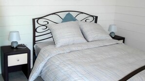 A neatly made bed with a striped bedspread, two bedside tables with lamps, and a wall-mounted flower artwork. - LE Chalet - Bazeilles (BAZEILLES)