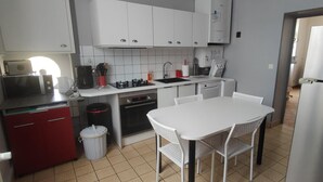 Una cuina compacta amb armaris blancs, microones, cafetera, rentapelats i nevera.