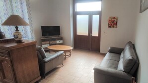 Un saló amb un sofà, una taula petita, un televisor i un armari.