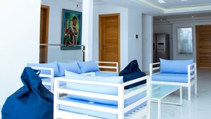 A spacious, modern living area with a high ceiling and a glass railing overlooking the interior. There are two white sofas with blue cushions and a blue bean bag chair. - Villa somone waterfront (Somone)