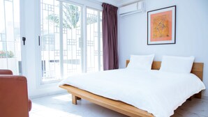 A bedroom with a large bed, a wooden headboard, a window with a view of palm trees, and a framed artwork on the wall. - Villa somone waterfront (Somone)