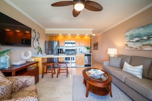 A modern living room with a sofa, coffee table, and a TV. - Oceanfront Corner Kuleana 409 Top-Floor Views, A/C, Pool, Tennis (Lahaina)