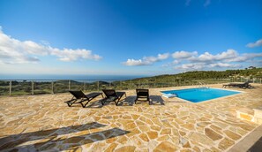 A stone patio with a pool and lounge chairs overlooking a scenic landscape. - Orient Villas Traditional (Zakynthos)