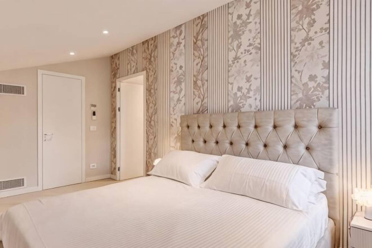 Un dormitorio con una cama grande, un cabecero capitonado y una puerta con un respiradero.