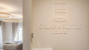 A hotel interior with a tufted headboard bed, a wall-mounted sign reading "Dimora Storia," and a reception desk. - Oriana Homèl Udine (Udine)