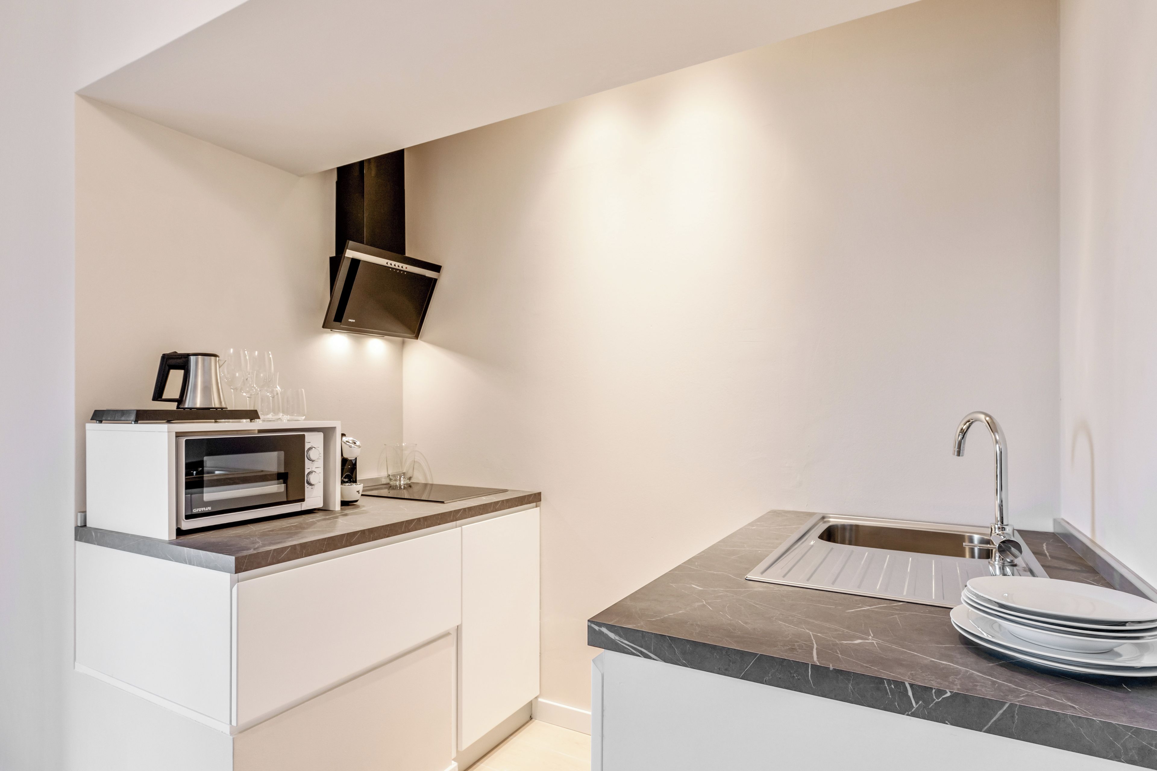 A modern kitchen with a built-in oven, a microwave, a coffee maker, and a sink.