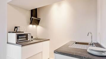 A modern kitchen with a built-in oven, a microwave, a coffee maker, and a sink.