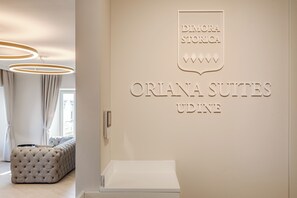 A hotel interior with a sign for 'Orlana Suites Udine' and a tufted sofa in the foreground. - Oriana Homèl Udine (Udine)