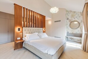 Un dormitorio moderno con una cama grande, cabecera de madera, mesitas de noche, un banco empotrado, un espejo redondo y una lámpara decorativa.
