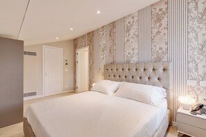 Un dormitorio con una cama grande, un cabecero capitonado, una mesita de noche con lámpara y una puerta con ventana.