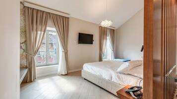Un dormitorio con cama, televisión montada en la pared y ventana con cortinas.
