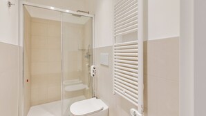 Un baño moderno con ducha de vidrio, inodoro blanco y toallero.