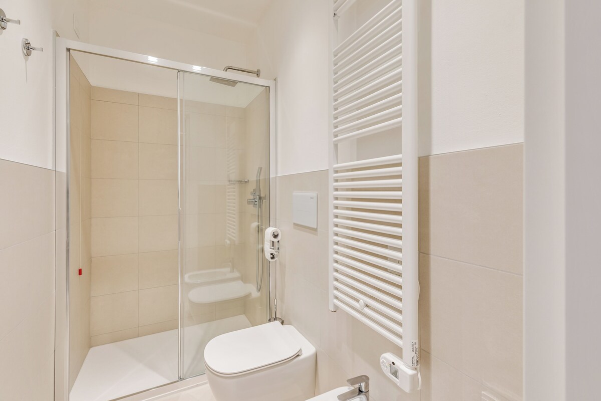 Un baño moderno con ducha de vidrio, inodoro blanco y toallero.