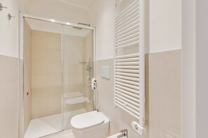 A modern bathroom with a glass-enclosed shower, a white toilet, and a towel rack. - Oriana Homèl Udine (Udine)