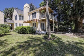 Une maison à deux étages dotée d’un porche et d’un petit espace extérieur aménagé pour s’asseoir.