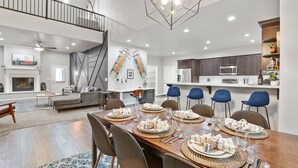 Amplia sala de estar con chimenea, una mesa de comedor preparada para seis personas y una cocina con electrodomésticos modernos.