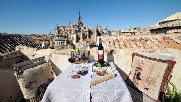 A rooftop terrace with a table set for two, featuring a bottle of wine, glasses, a menu, and a decorative item. - Céntrico impresionante ático con vistas del cathedral  (Toledo)