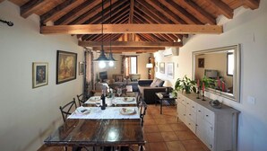 A dining area with a wooden table, chairs, and a ceiling with exposed beams. - Céntrico impresionante ático con vistas del cathedral  (Toledo)